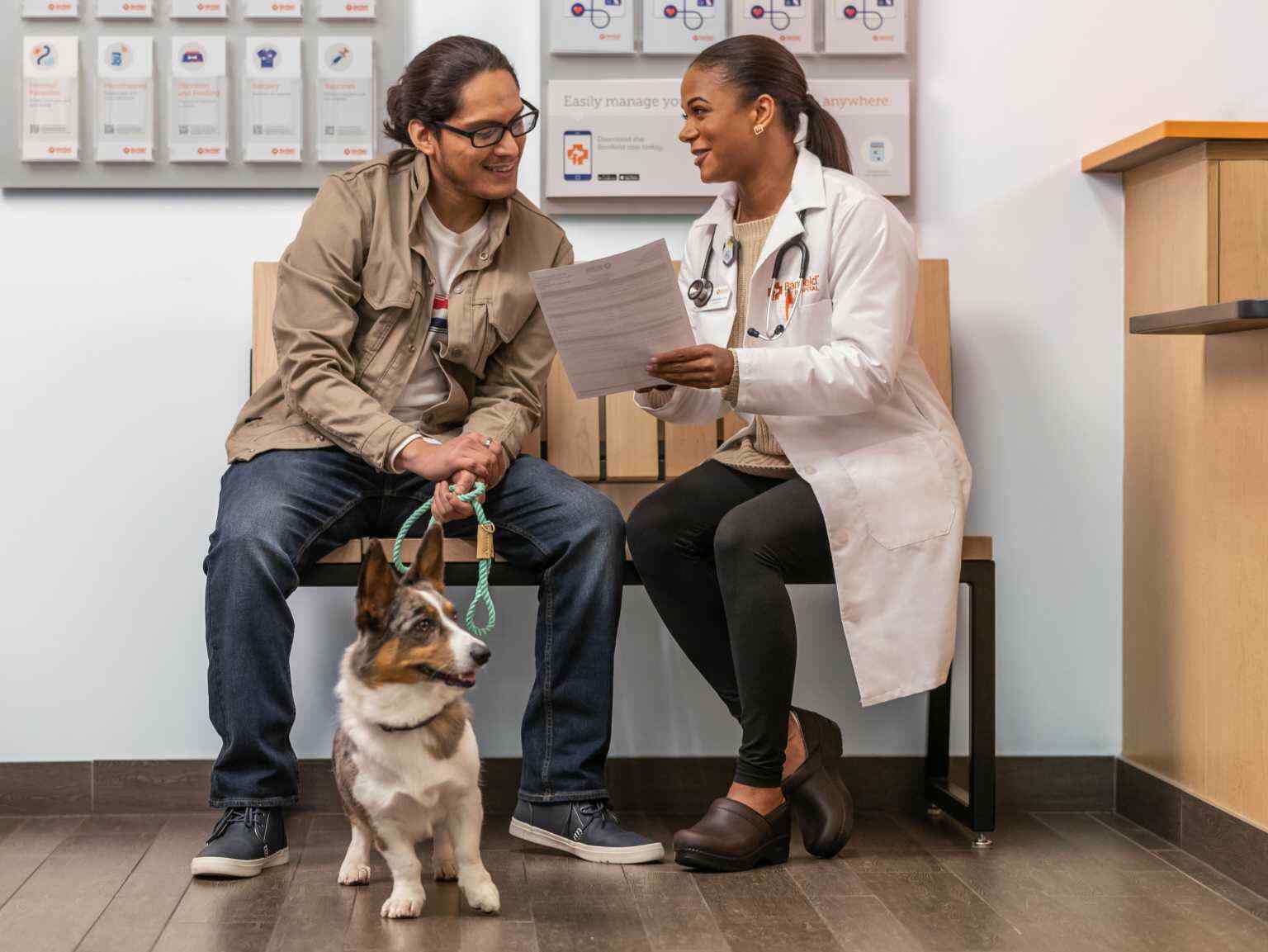 A female veterinarian explaining a medical report to a dog owner, who is holding his dog on a leash at the Banfield Pet Hospital