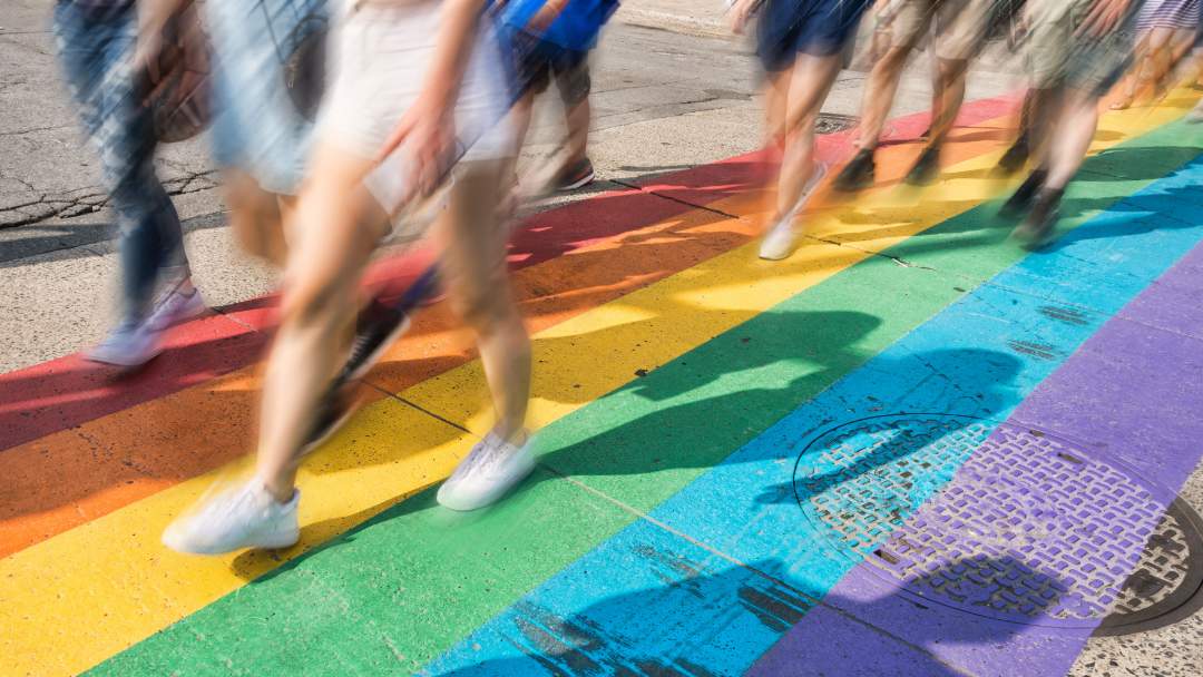 People walking on rainbow street for Pride Month