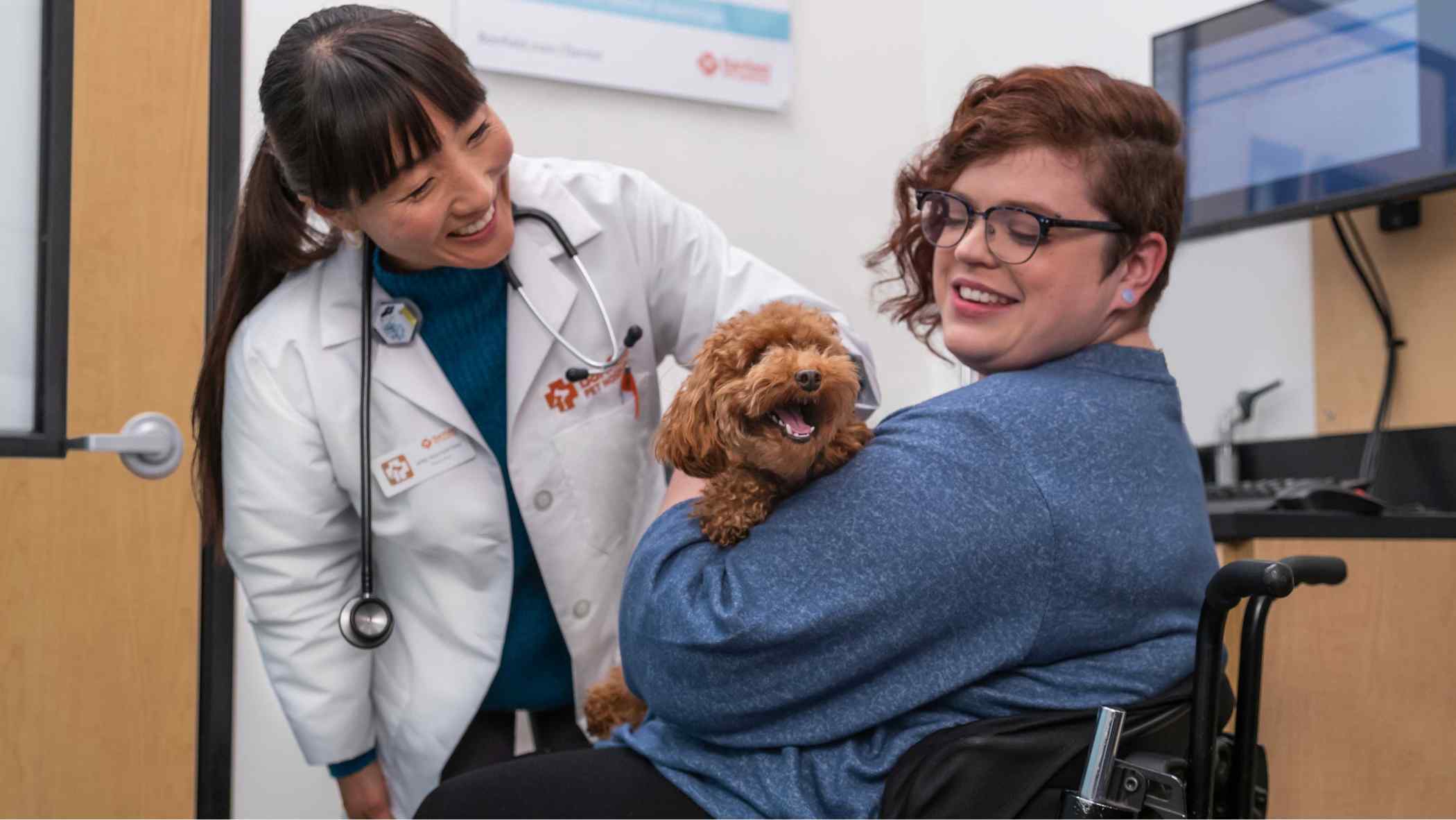 Veterinarian and pet owner petting small dog.