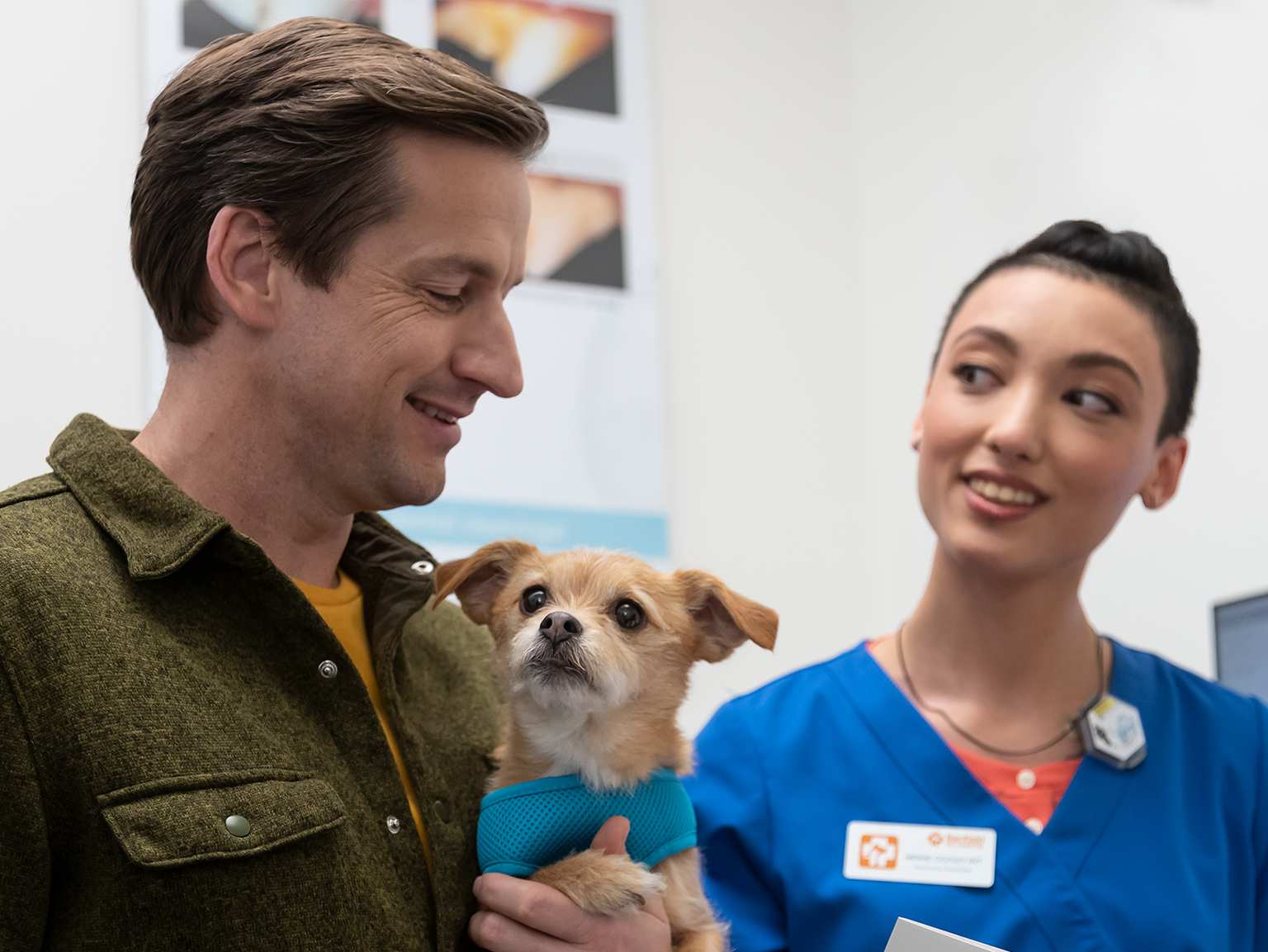 A happy man holding his puppy and interacting with a young female veterinarian at the Banfield Pet Hospital