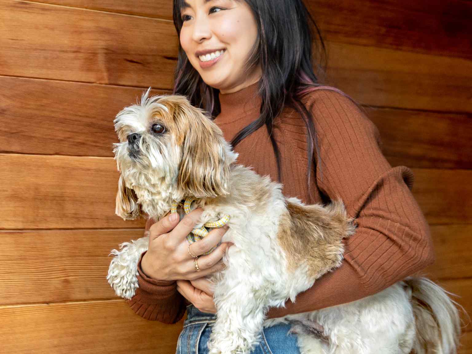 A young woman carrying her furry little dog