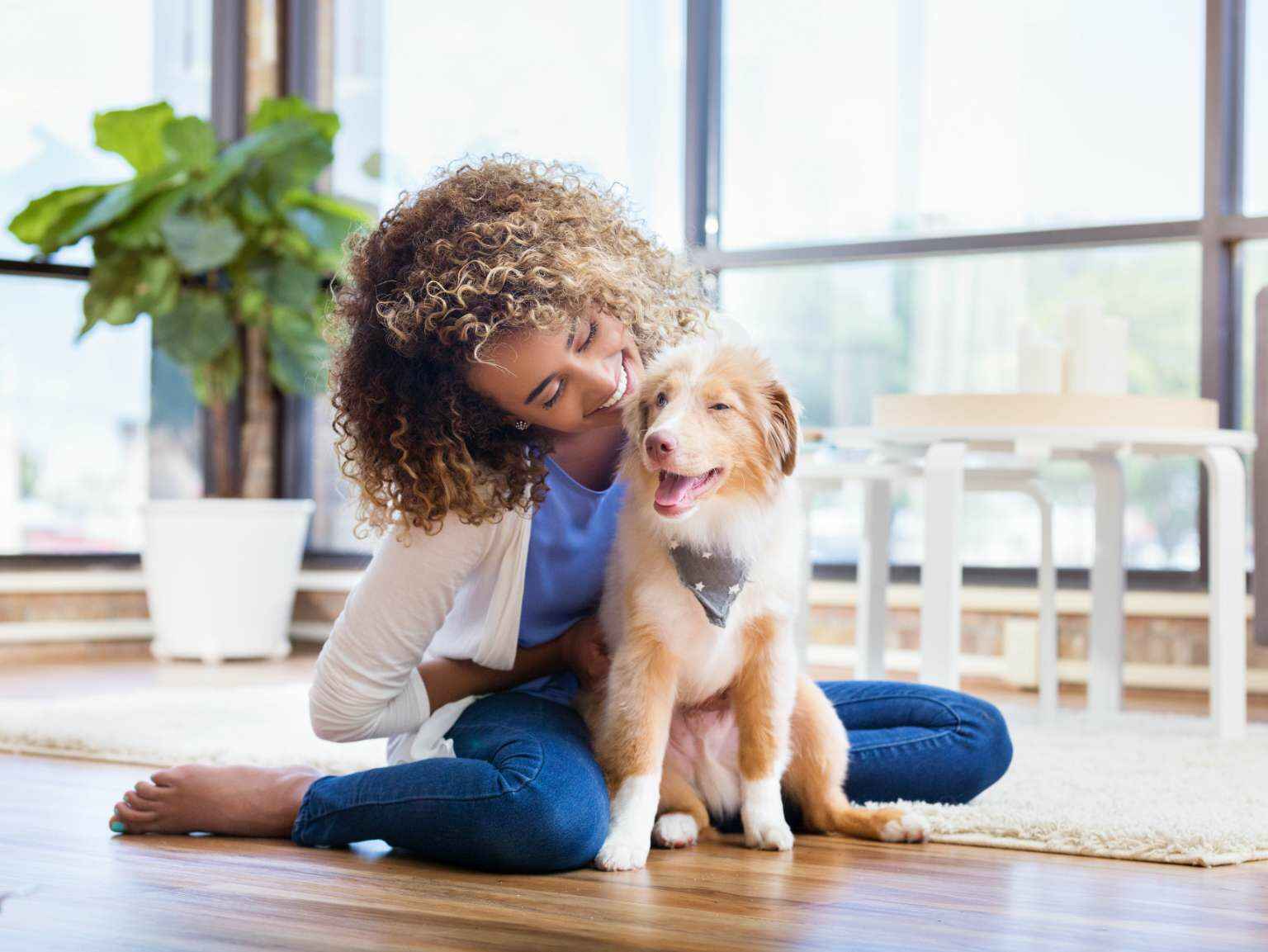 miling woman sits on floor with fluffy puppy